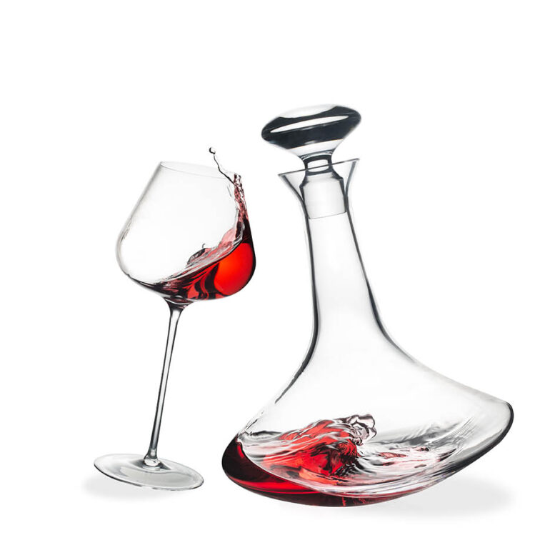 Karafa in kozarec za rdeče vino z gibajočo se tekočino, produktna fotografija na beli podlagi